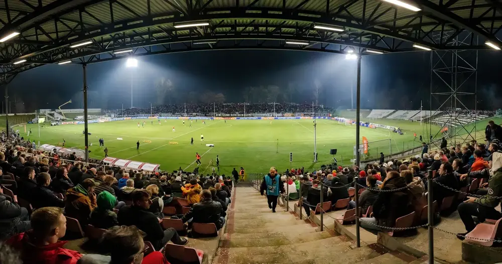 Estádio de futebol iluminado à noite com arquibancada cheia