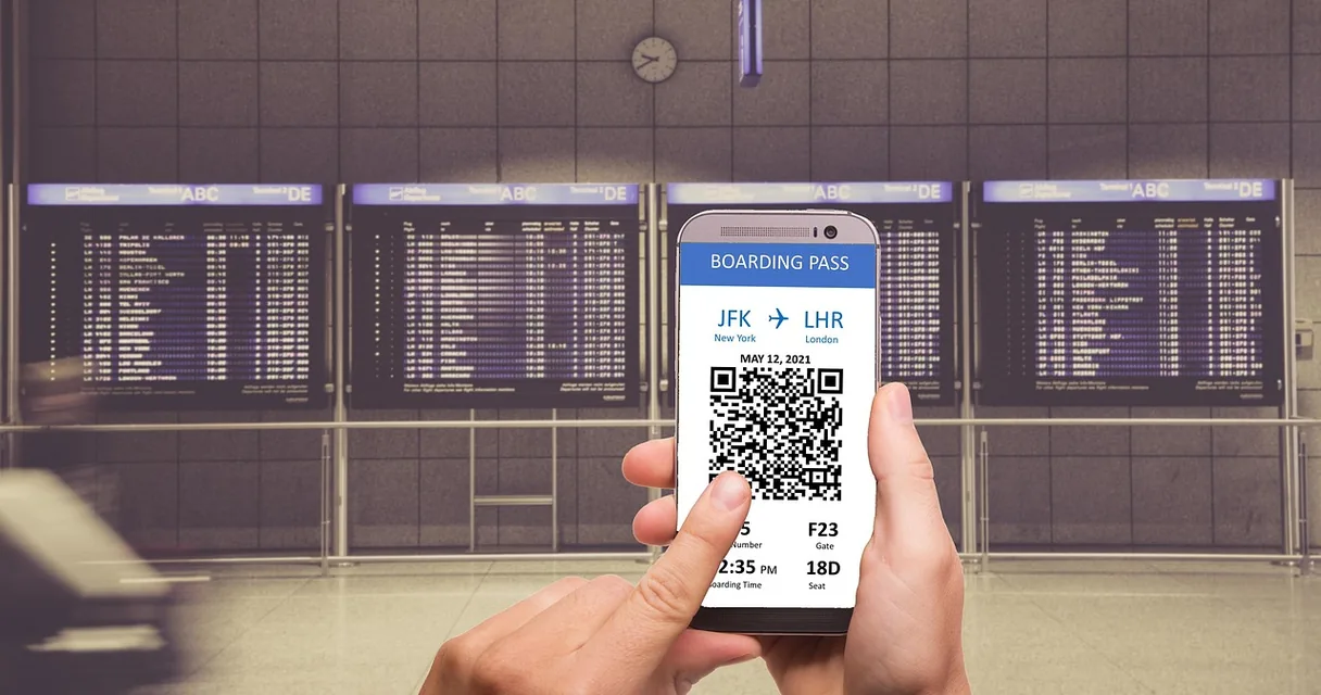 Mão segurando celular com cartão de embarque digital e QR Code em um aeroporto